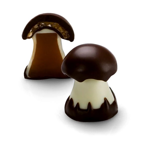 Two chocolate mushroom candies. One is cut open showing caramel and nuts inside.
