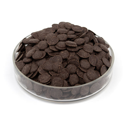 A pile of dark brown chocolate wafers in a clear round glass container, photographed on a white background.