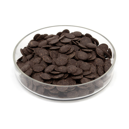 A pile of dark brown chocolate wafers in a clear round glass container, photographed on a white background.