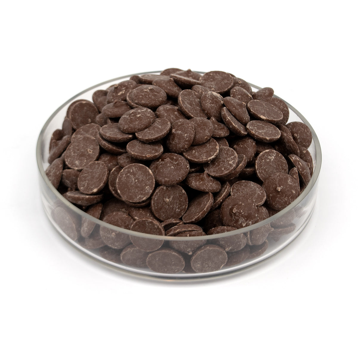 A pile of dark chocolate wafers in a glass bowl photographed on a white background