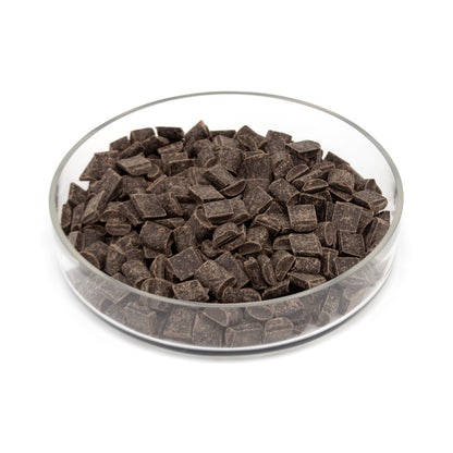 Dark chocolate chunks in a clear glass bowl on a white background.