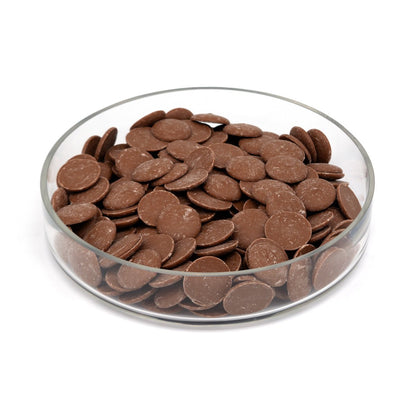 Glass bowl filled with chocolate discs on a white background