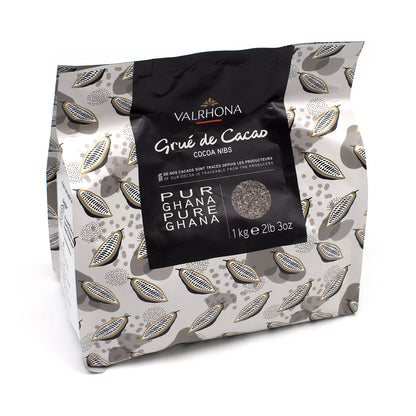 A 1 kg (2.2 lb) bag of Valrhona Grúe de Cacao Cocoa Nibs from Ghana, featuring a black central label on a gray and white patterned background.