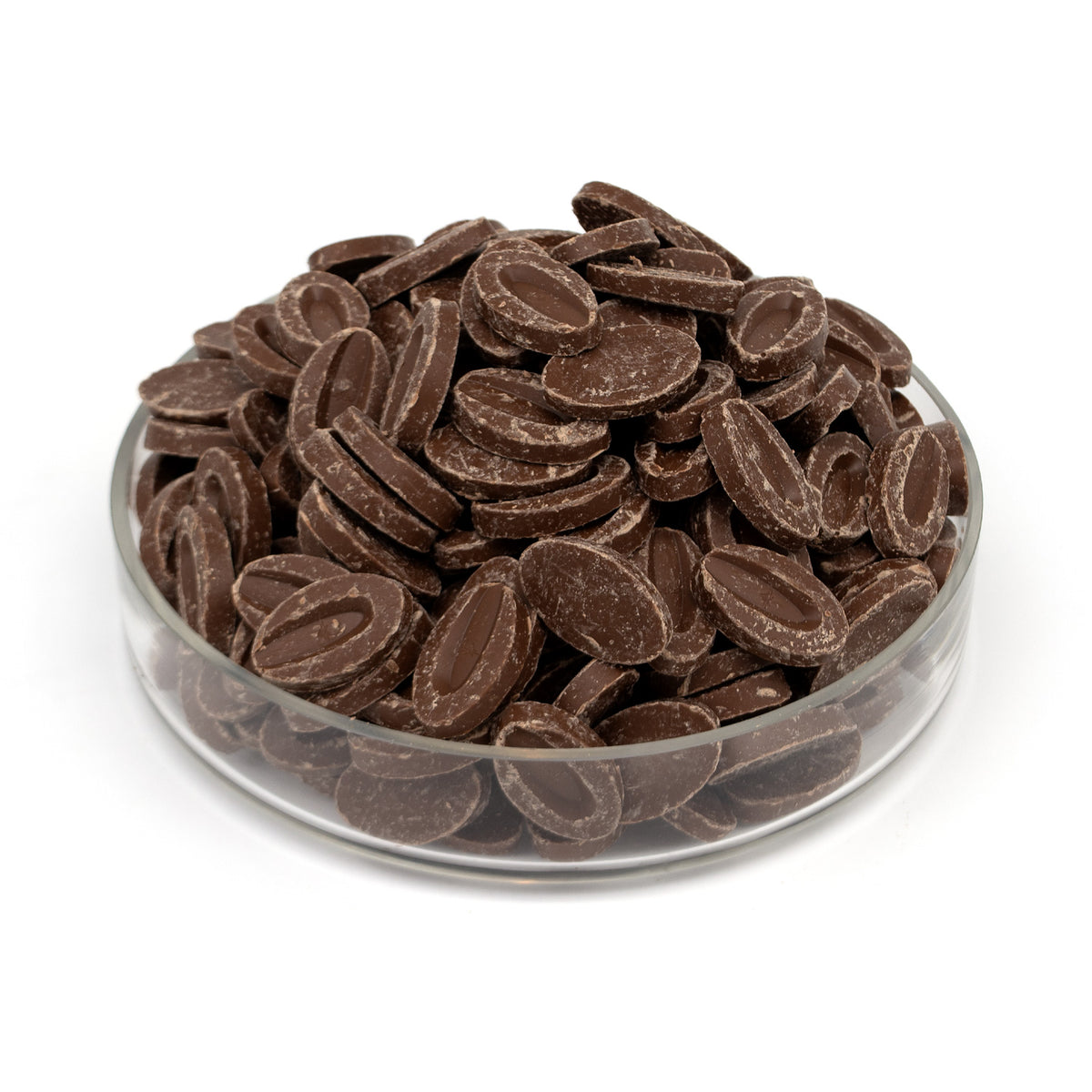 Milk chocolate discs piled in a clear glass bowl on a white background.