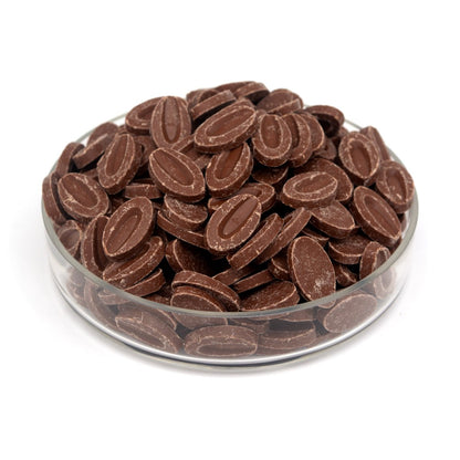 Chocolate feves in a clear glass bowl on a white background